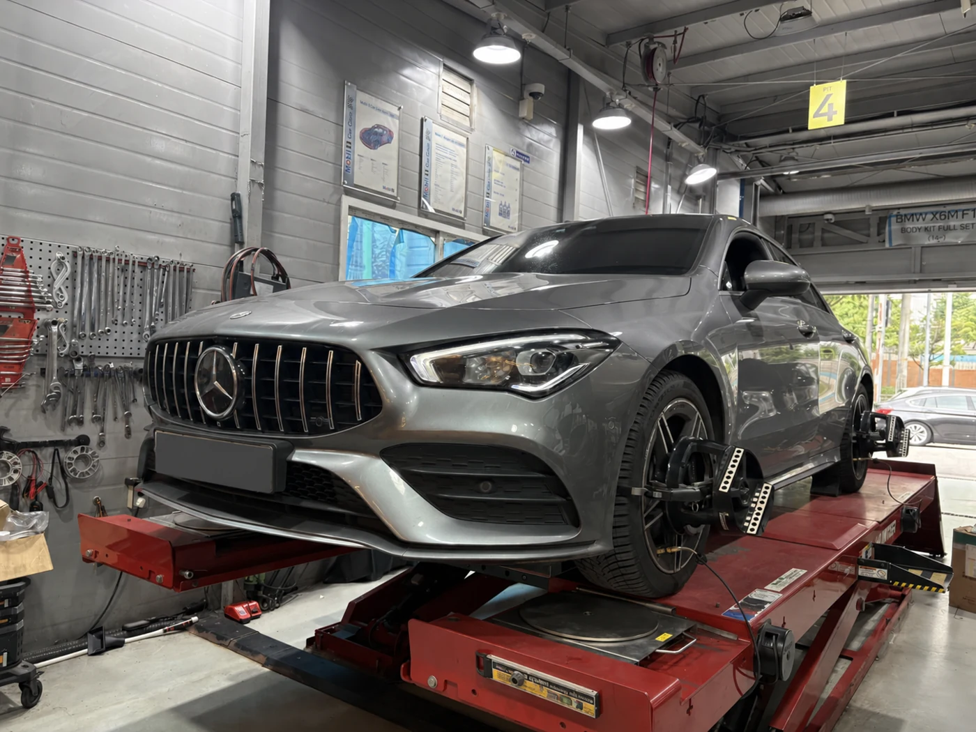 The Mercedes CLA 250 on the alignment lift. Licence plate obscured.