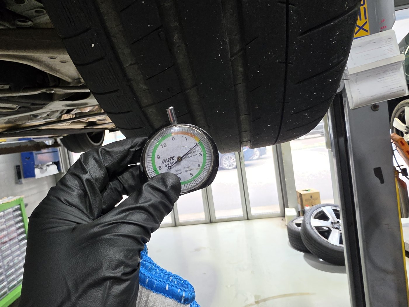 Placing a depth gauge in the tire groove to check the remaining tread depth.