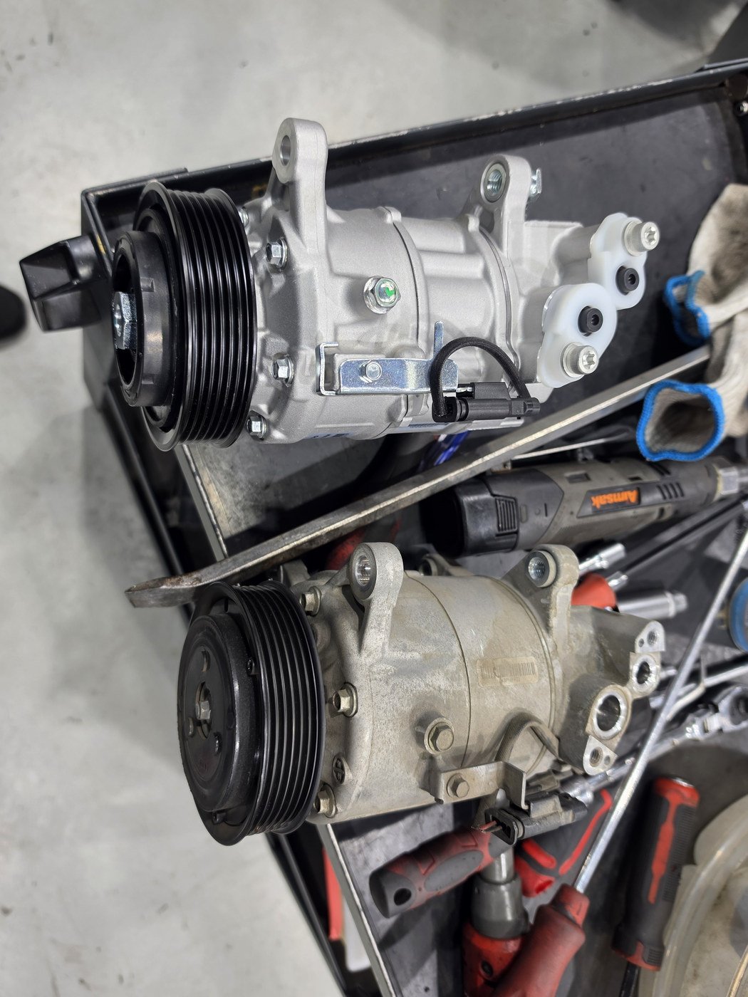 Comparing the mounting points of the removed compressor and the new replacement
