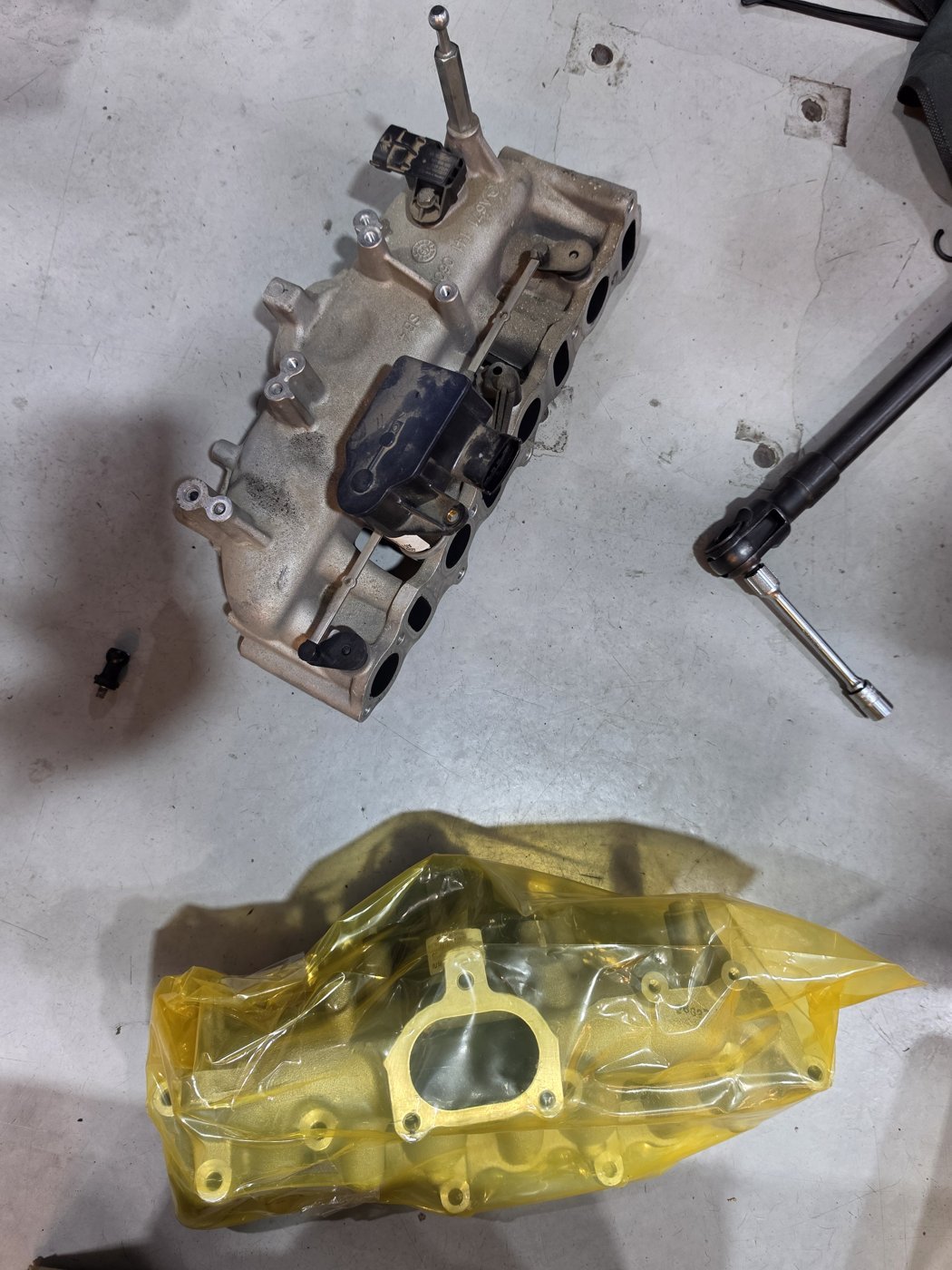 The removed intake manifold and the replacement part.