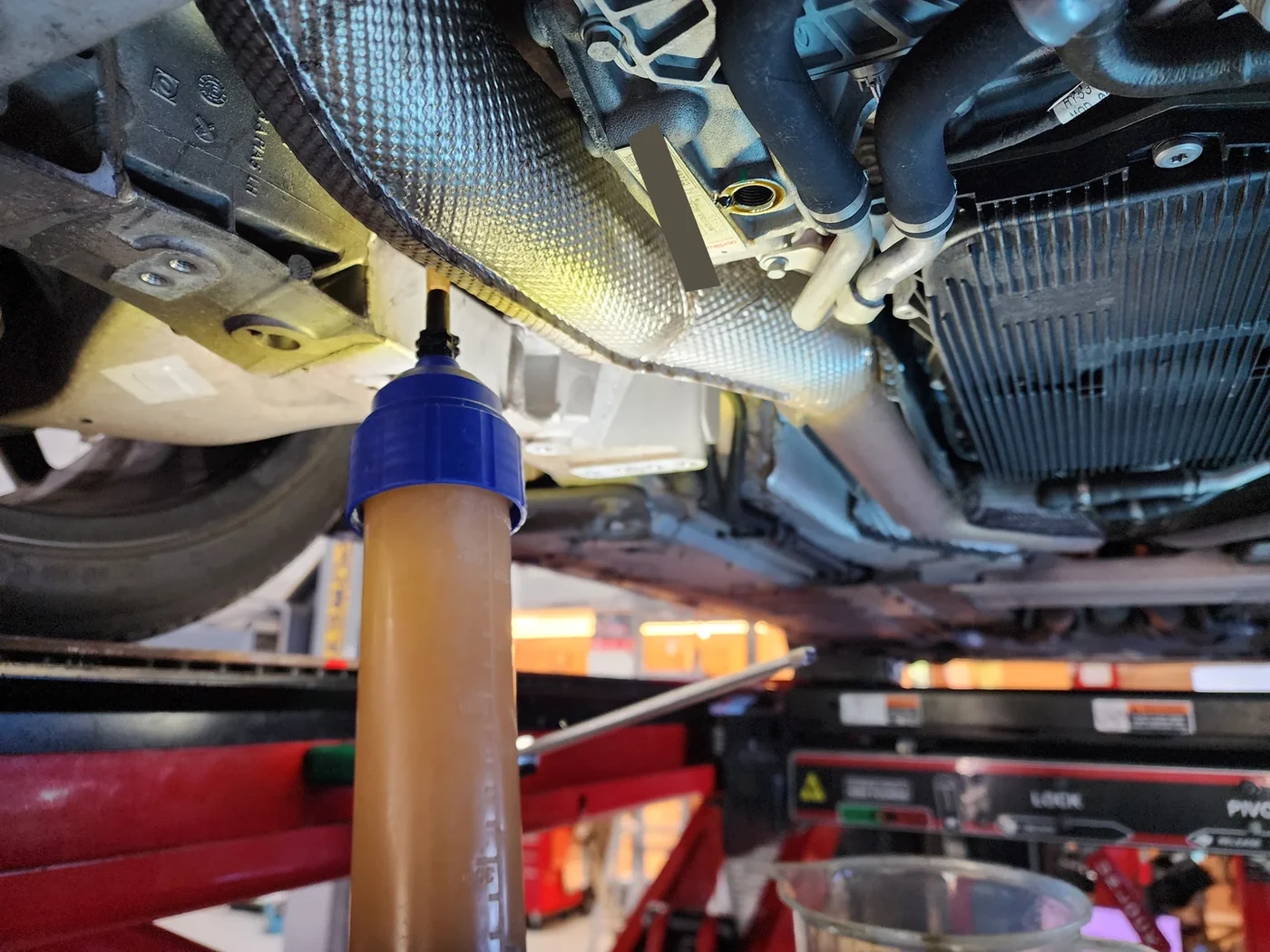 A syringe connected at the differential filler opening during the oil service.