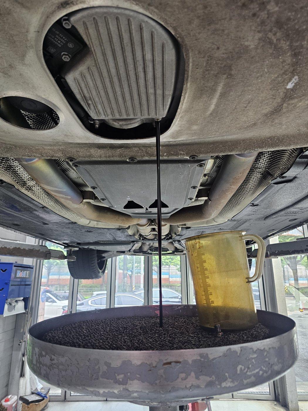 Used engine oil draining from the outlet under the engine