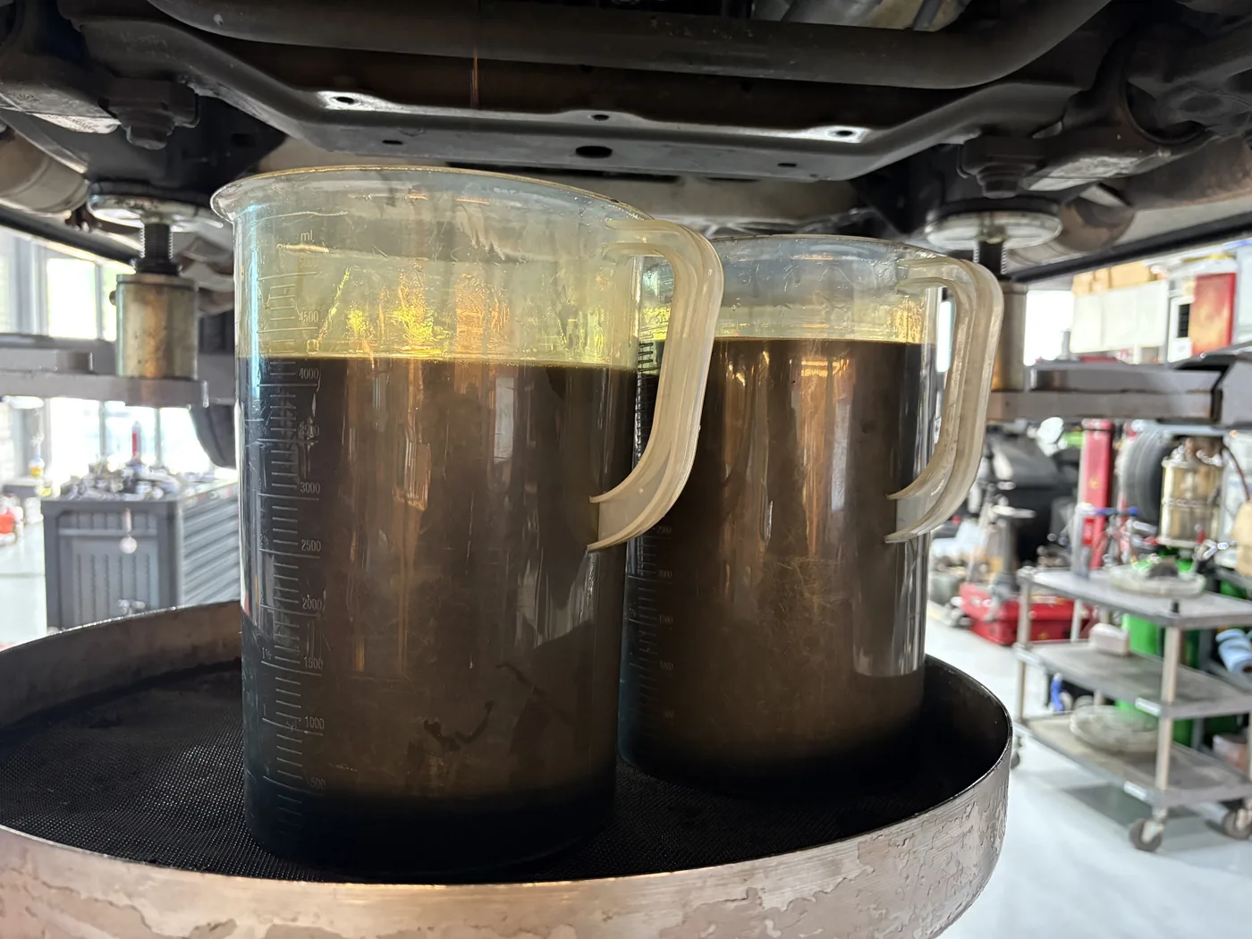 Drained engine oil collected in graduated containers for inspection.