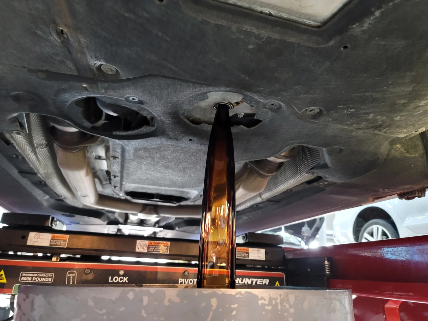 Draining the existing engine oil from beneath the vehicle